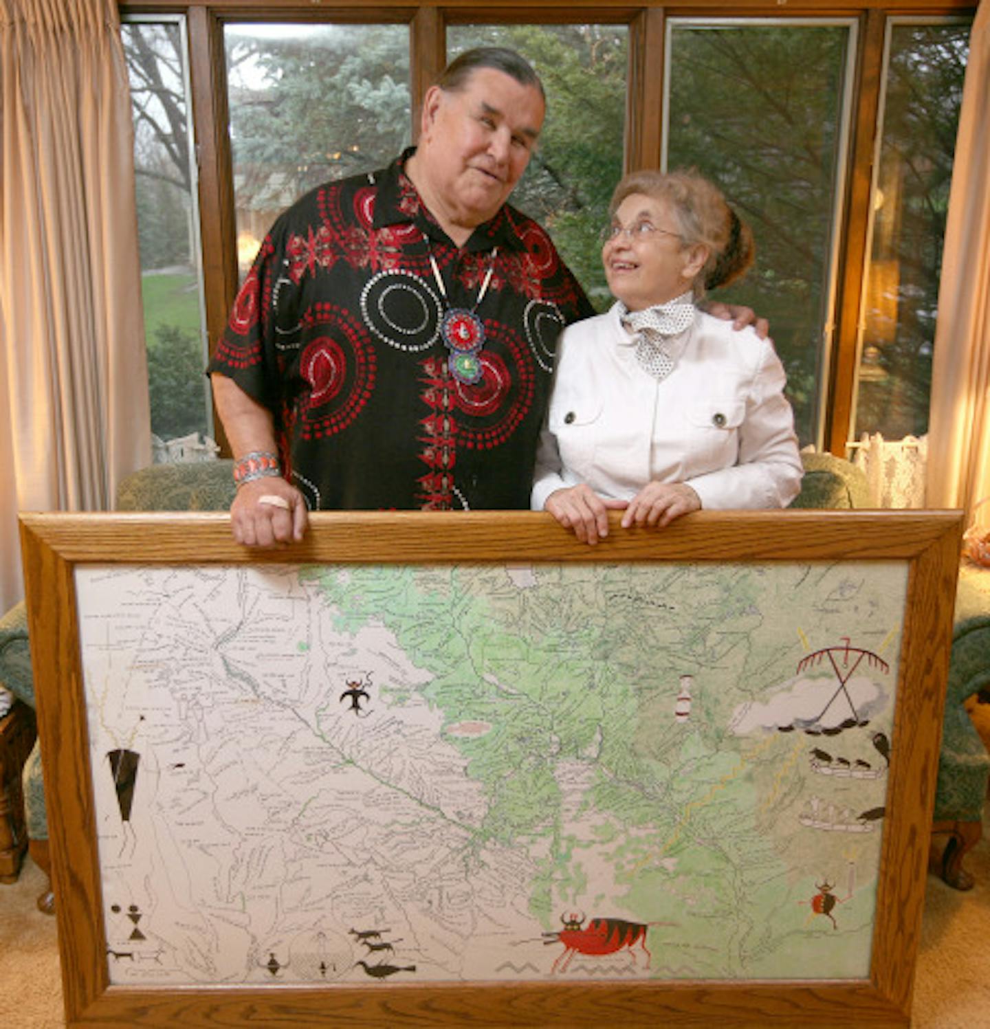 Clyde Bellecourt and Dorothy Durand display Paul Durand's map at her Faribault home. The map covers all of southern Minnesota and parts of Wisconsin.