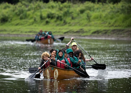 Despite a light rain, Celicia Morris (front right) had a smile on her face as they paddled down the Mississippi River. The day trip was part of the Science Museum's Minnesota Earth Defenders Camp.