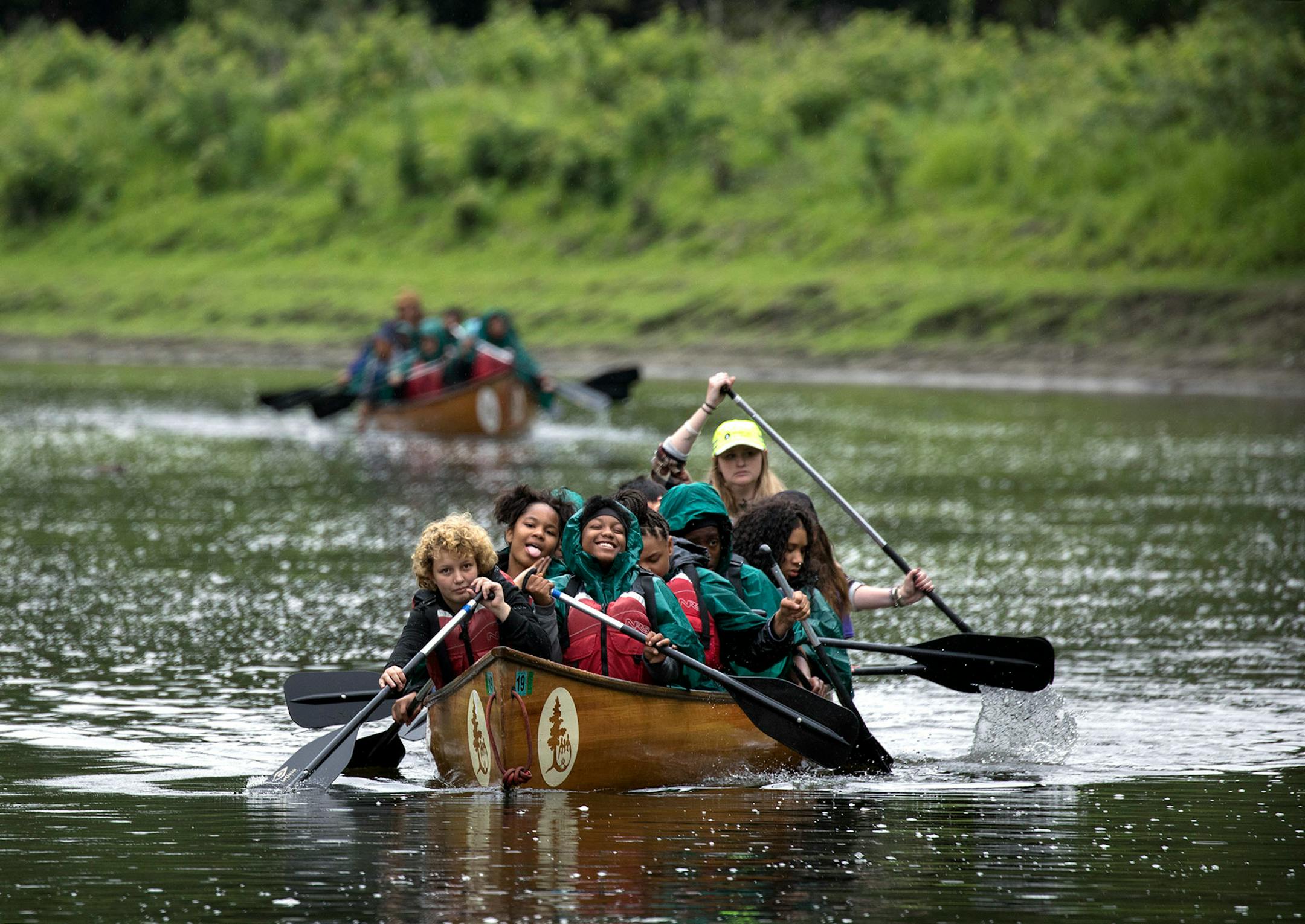 Despite a light rain, Celicia Morris (front right) had a smile on her face as they paddled down the Mississippi River. The day trip was part of the Science Museum's Minnesota Earth Defenders Camp.