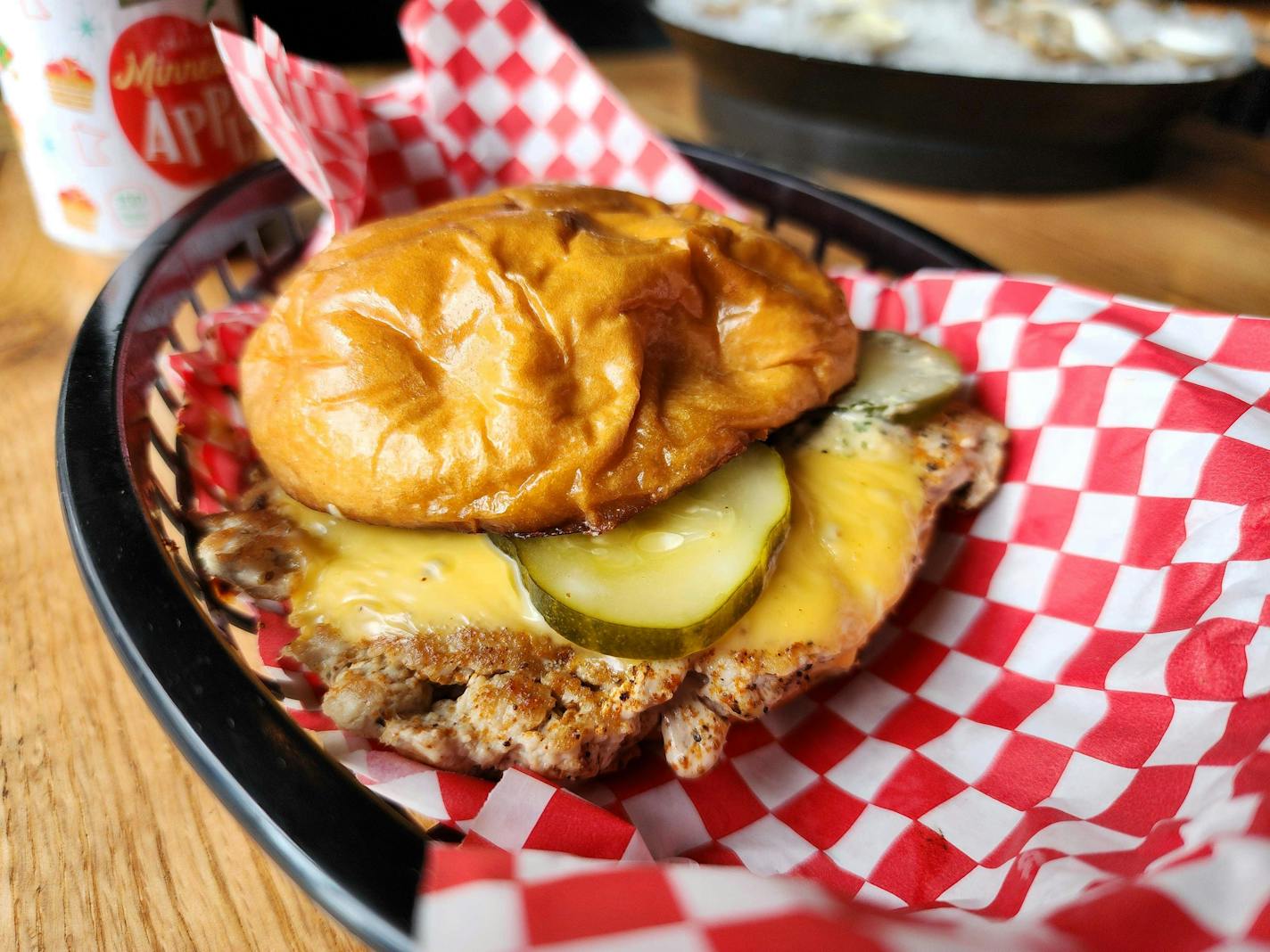 A cheeseburger where the meat is lighter and pinker than usual because it's made from tuna, in a basket with red-and-white checkered paper