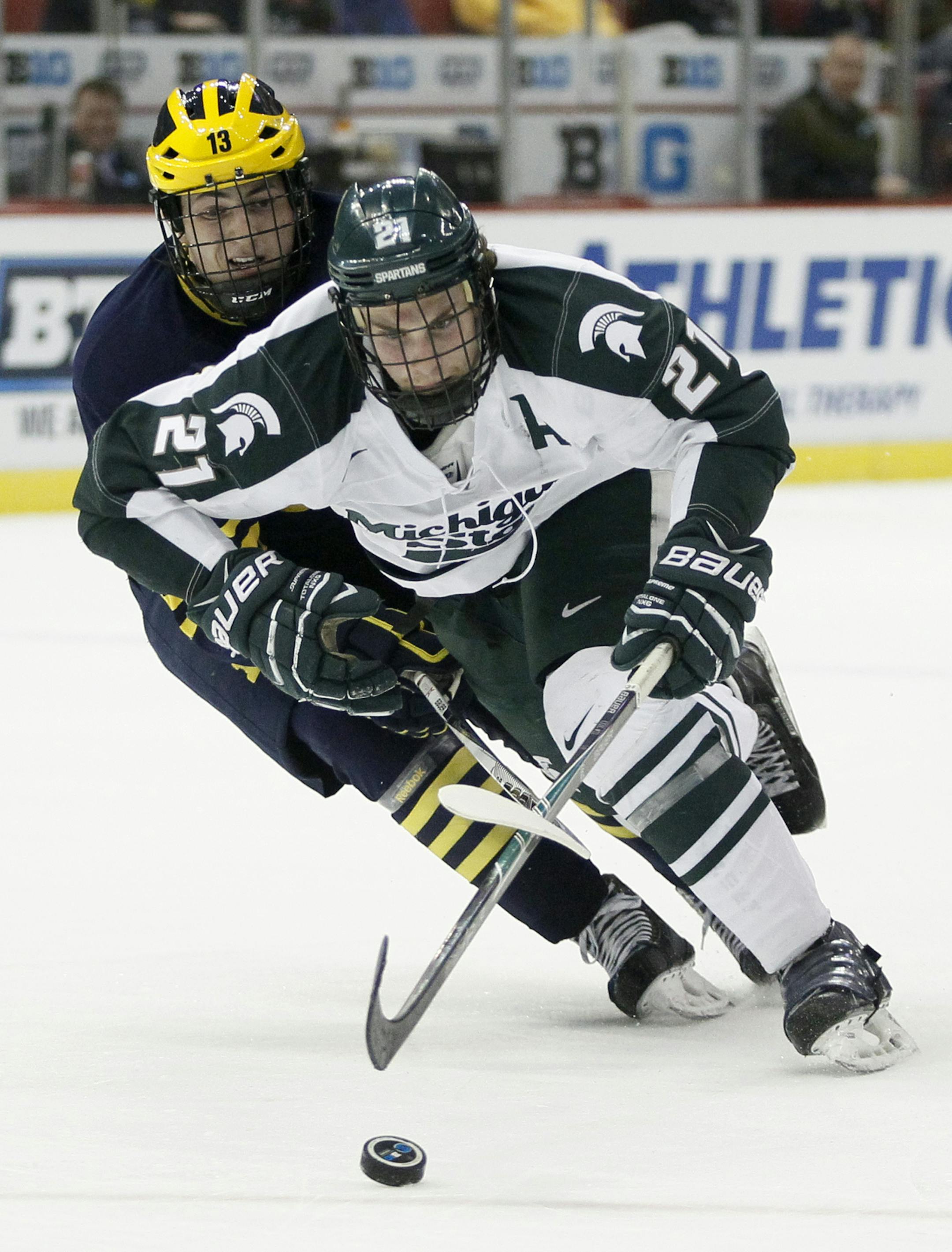 Michigan's Zach Werenski (13) tries to knock Michigan State's Joe Cox (21) off the puck during the second period of an NCAA college hockey game in the Big Ten Conference tournament Friday, March 20, 2015, in Detroit. (AP Photo/Duane Burleson)