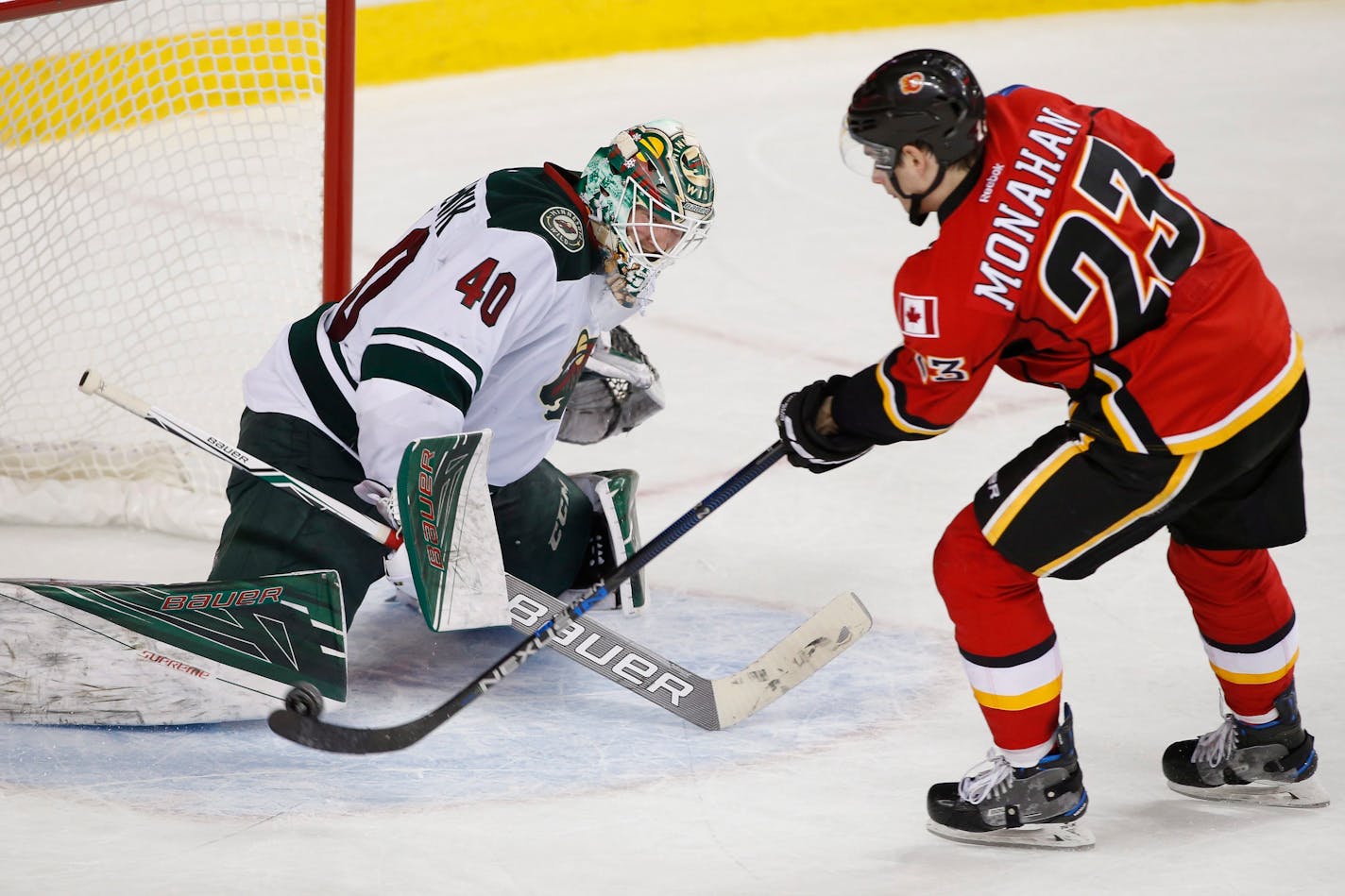 Calgary Flames' Sean Monahan, right, scores against Minnesota Wild goalie Devan Dubnyk during the shootout in an NHL hockey game in Calgary, Alberta, Friday, Dec. 2, 2016. (Larry MacDougal/The Canadian Press via AP)