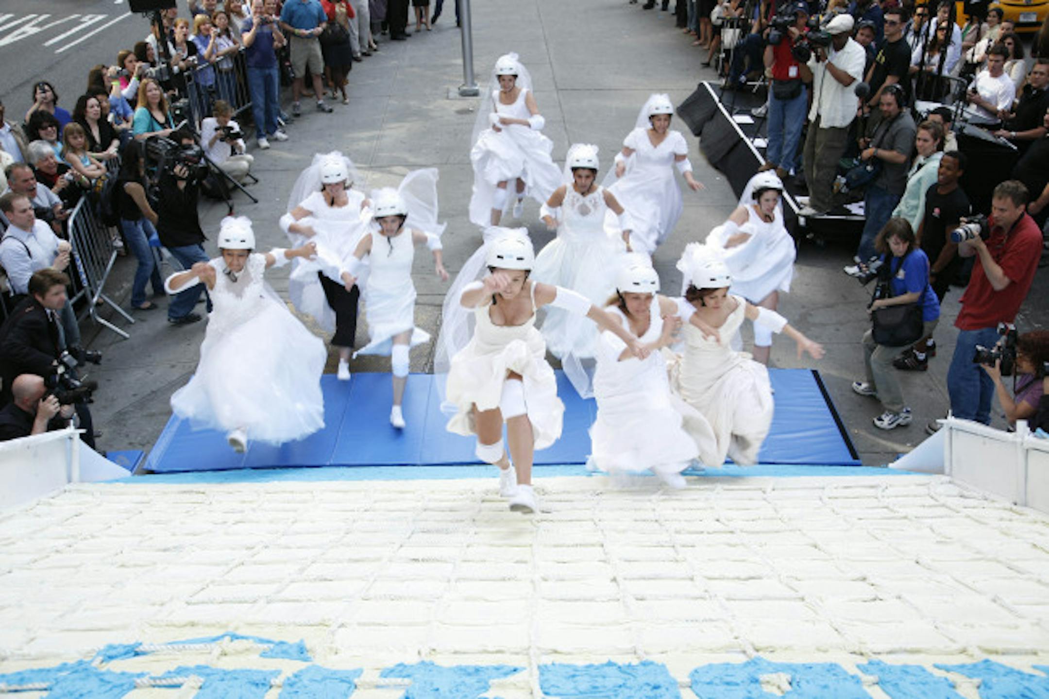 File photo: Brides run up a 10-foot high slice of wedding cake as part of a contest.
