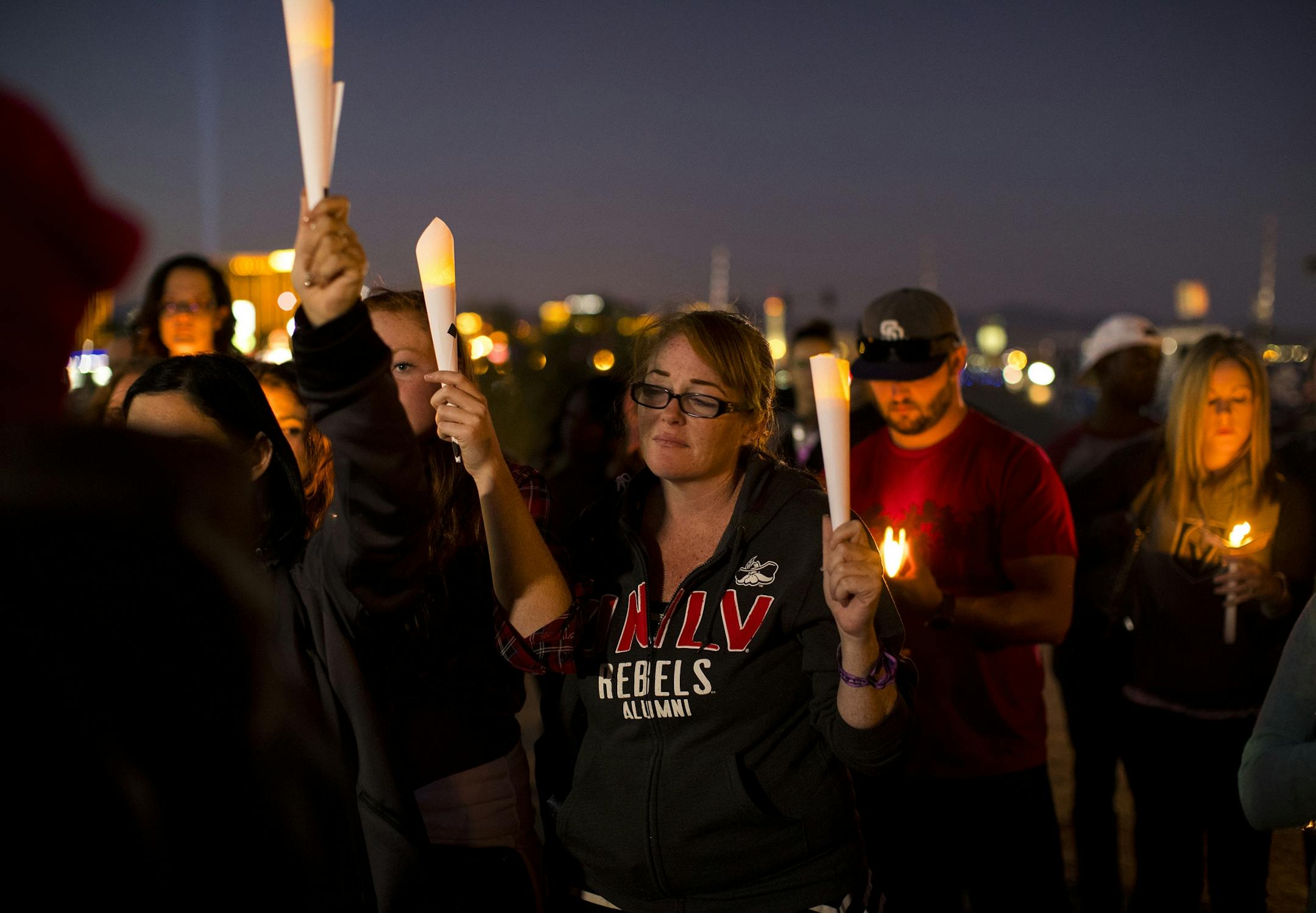 Concert goer Allie Sibley of Upland, middle, attends a candlelight vigil at Town Square to remember those killed and injured.
