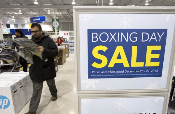 A shopper reads a flyer on Boxing Day at Best Buy in Ottawa on Thursday, Dec. 26, 2013. Boxing Day, observed in Canada, the United Kingdom, and other 