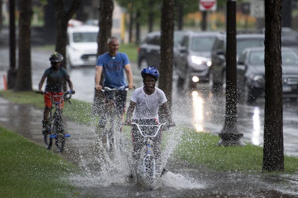 Cornell Smith, 11, pedaled fast through flooding along Dunwoody Boulevard on Tuesday on the way to a Twins game at Target Field. Smith and his brother