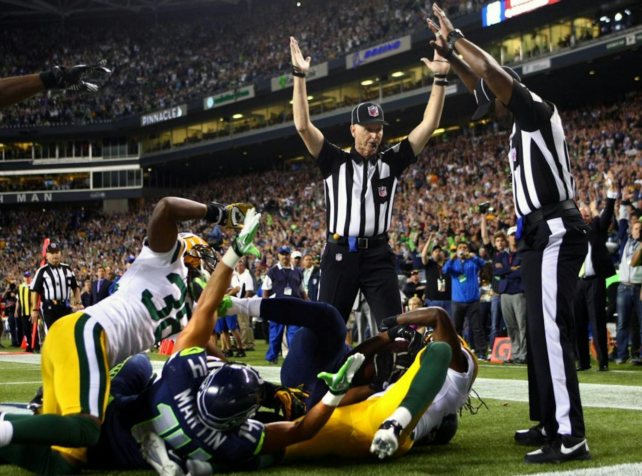 Officials signal after Seattle Seahawks wide receiver Golden Tate pulled in a last-second pass for a touchdown from quarterback Russell Wilson. The touchdown call stood after review.
