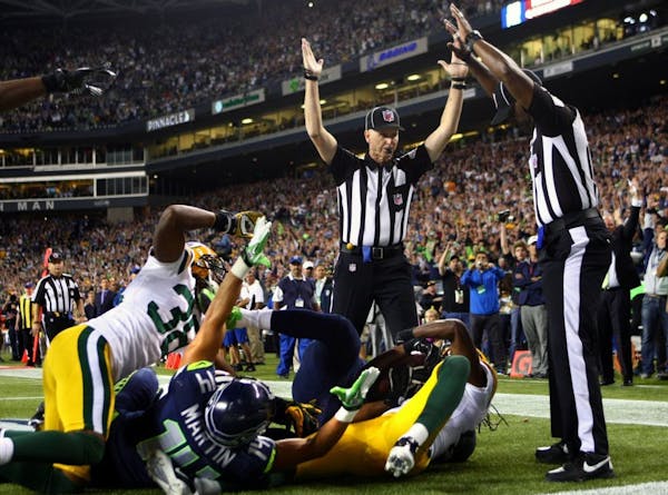 Officials signal after Seattle Seahawks wide receiver Golden Tate pulled in a last-second pass for a touchdown from quarterback Russell Wilson. The to