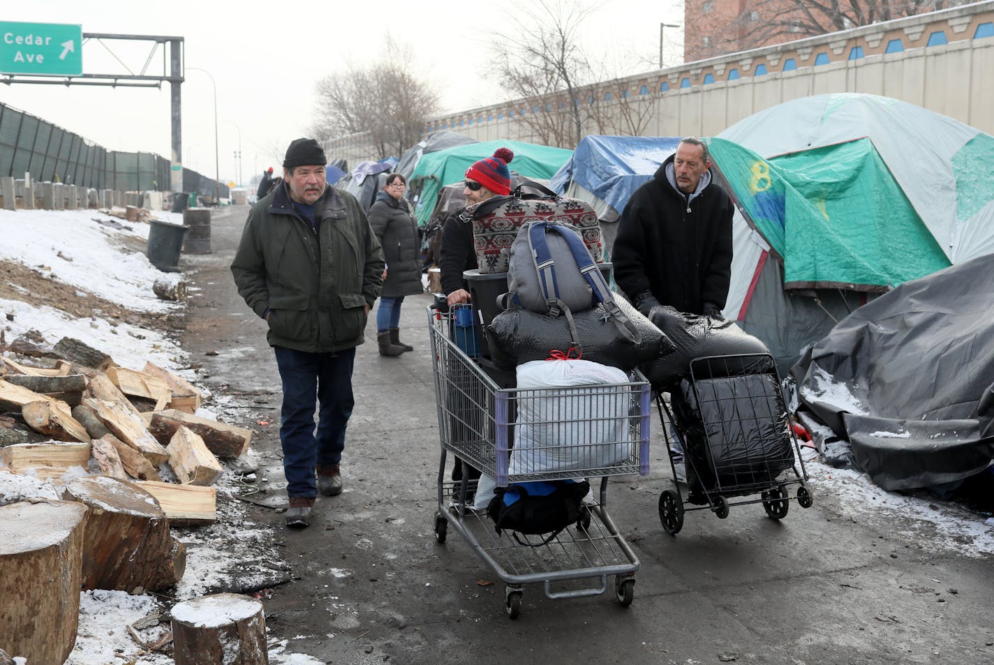 It was moving day for some at the Hiawatha homeless encampment and a day of joy and emotion for some Tuesday, Dec. 11, 2018, in Minneapolis, MN. Here, resident James Loerzel, 59, left, who has lived at the camp for about three months, has his life's possessions in a shopping cart as he got help moving to the new navigation center from members of Natives Against Heroin, including founder James Cross, right. Loerzel said he was looking forward to the move, especially being in a heated place.] DAVI