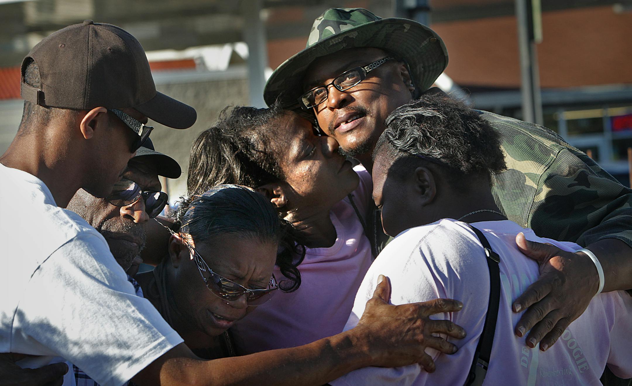 K.G. Wilson (top/middle) was embraced by supporters at the corner of W. Broadway and N. Lyndale Avenues in north Minneapolis, near where a woman was shot Tuesday evening. At the time of the Tuesday shooting, Wilson was leading a prayer vigil for peace.