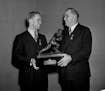 Captain of the University of Minnesota Bruce Smith, left, receives the Heisman trophy from Joseph R. Taylor of the Downtown Athletic Club in New York,