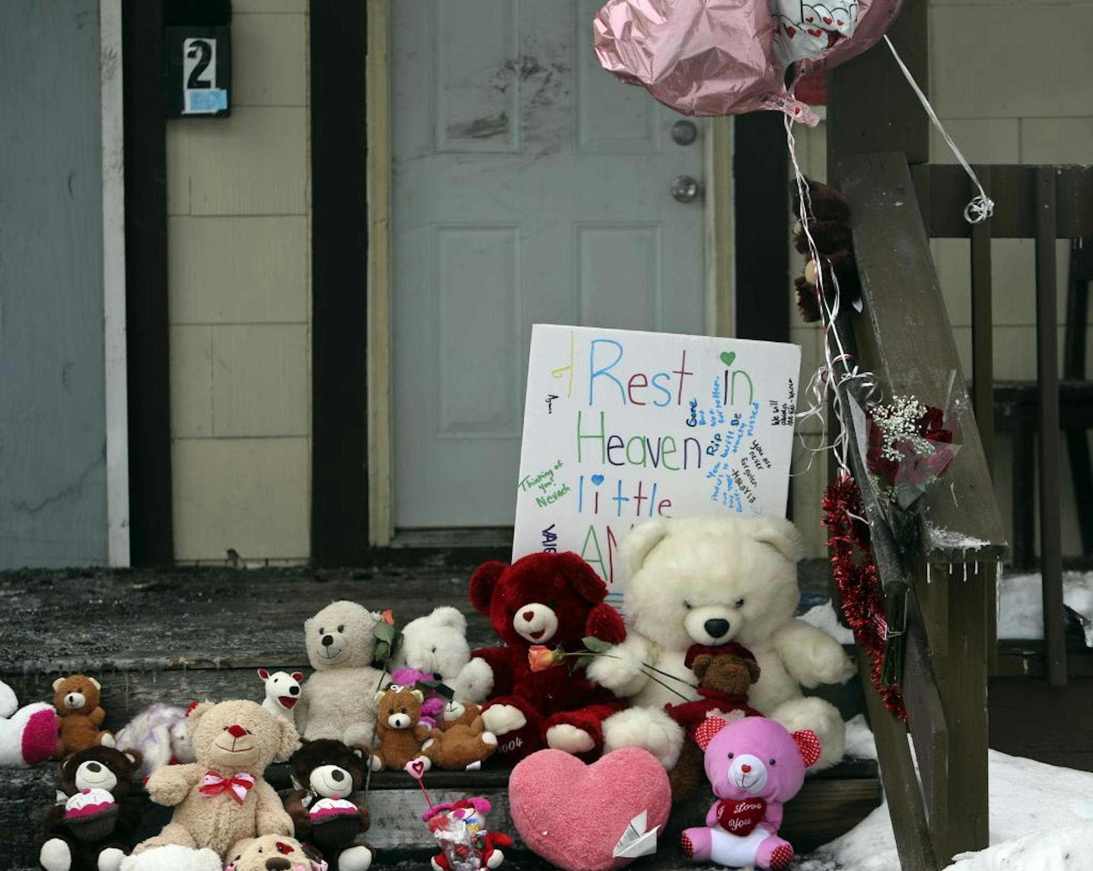 A day after the fire that took the lives of five, including three children, a growing collection of stuffed toys blocks the steps of the charred duplex Saturday, Feb. 15, 2014, in Minneapolis, MN.