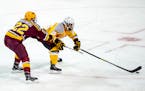 Colorado College defenseman Brady Smith, right, fights to maintain control of the puck as Gophers forward Bryce Brodzinski defends during the first pe