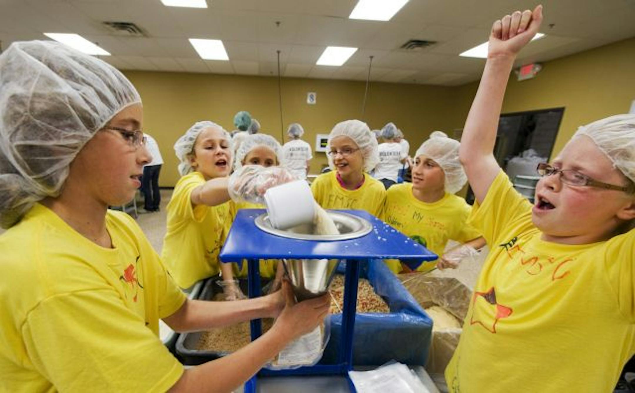 Partygoers at Hailey Pietsch's birthday party watched a Feed My Starving Children staff member show them how to seal the plastic bags they would be filling. The girls, who worked with a volunteer group from Target that day, filled hundreds of bags bound for Haiti and Guatemala.