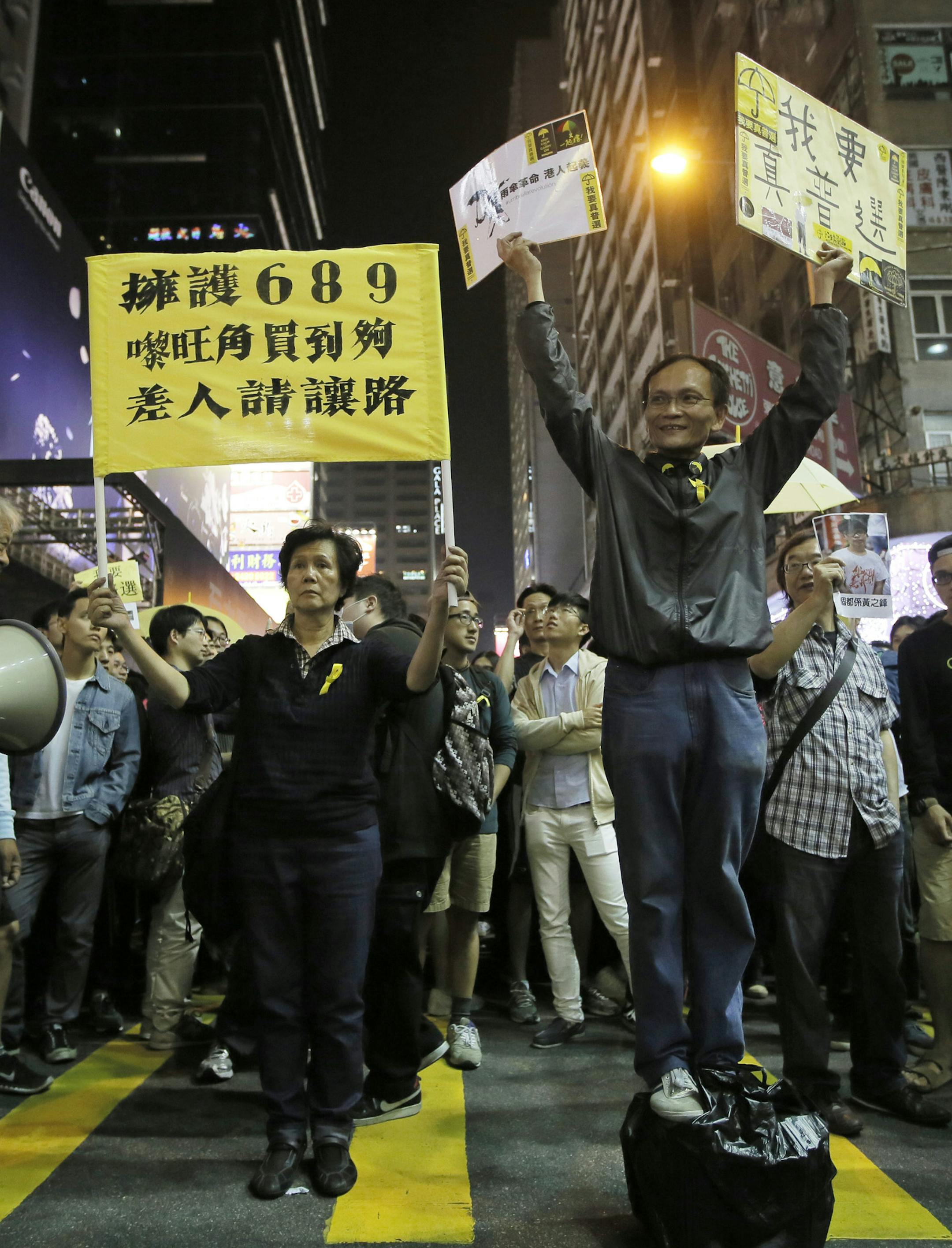 A protester raises a placard that reads "I want genuine universal suffrage" in Mong Kok district of Hong Kong Friday, Nov. 28, 2014. Scuffles broke out between pro-democracy demonstrators and police as protesters tried to force their way past police cordons. Several people were injured in the scuffles and arrested. (AP Photo/Vincent Yu)