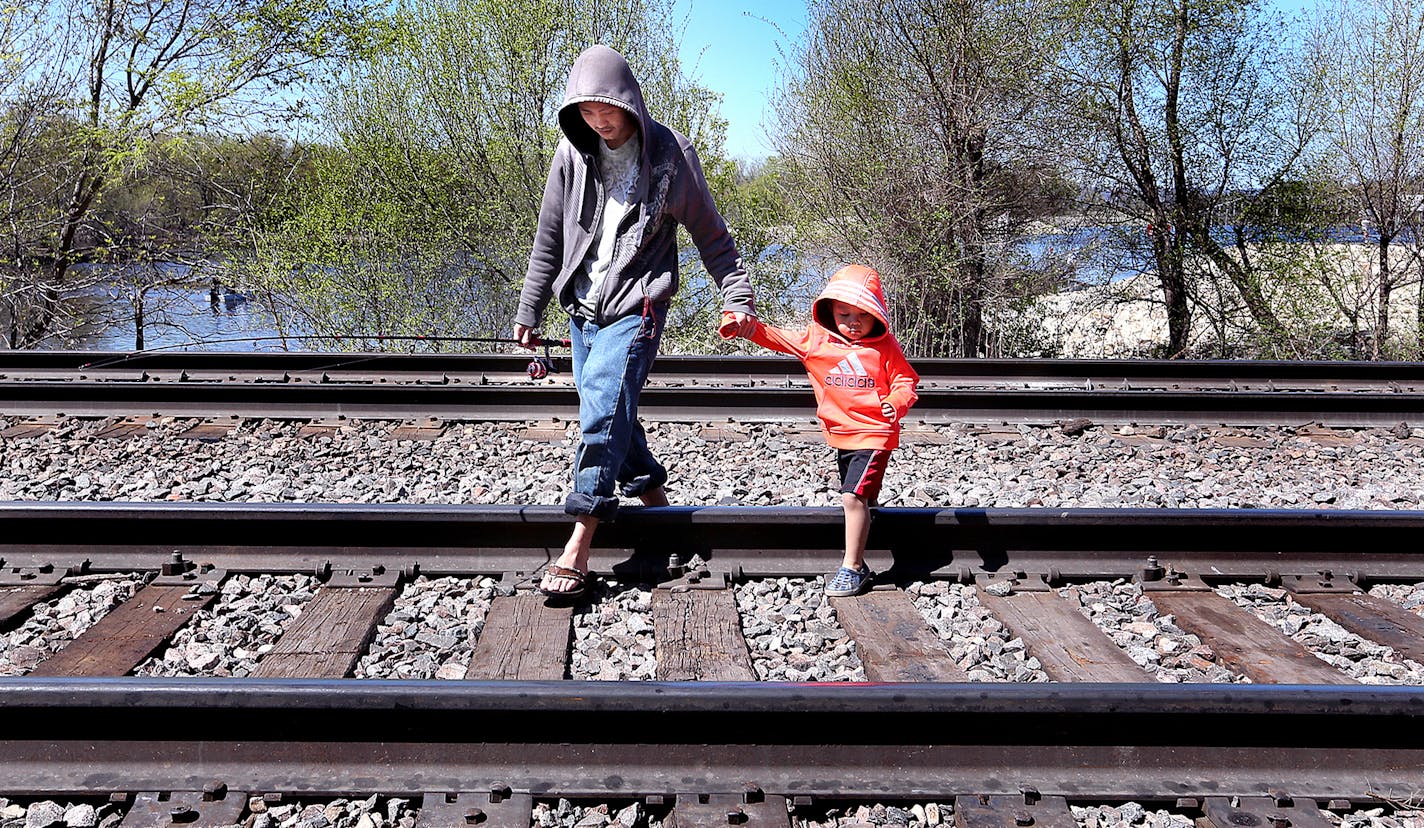 Hmong Vue and his nephew Chance Lor, 3, cross railroad tracks near the spillway in Onalaska after fishing at the popular spot. Anglers have no choice but to cross BNSF railroad tracks on foot in order to access the Spillway from Onalaska. Peter Thomson, La Crosse Tribune