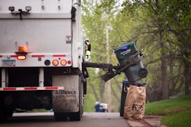 A trash collector empties containers onto the truck on trash pickup day.