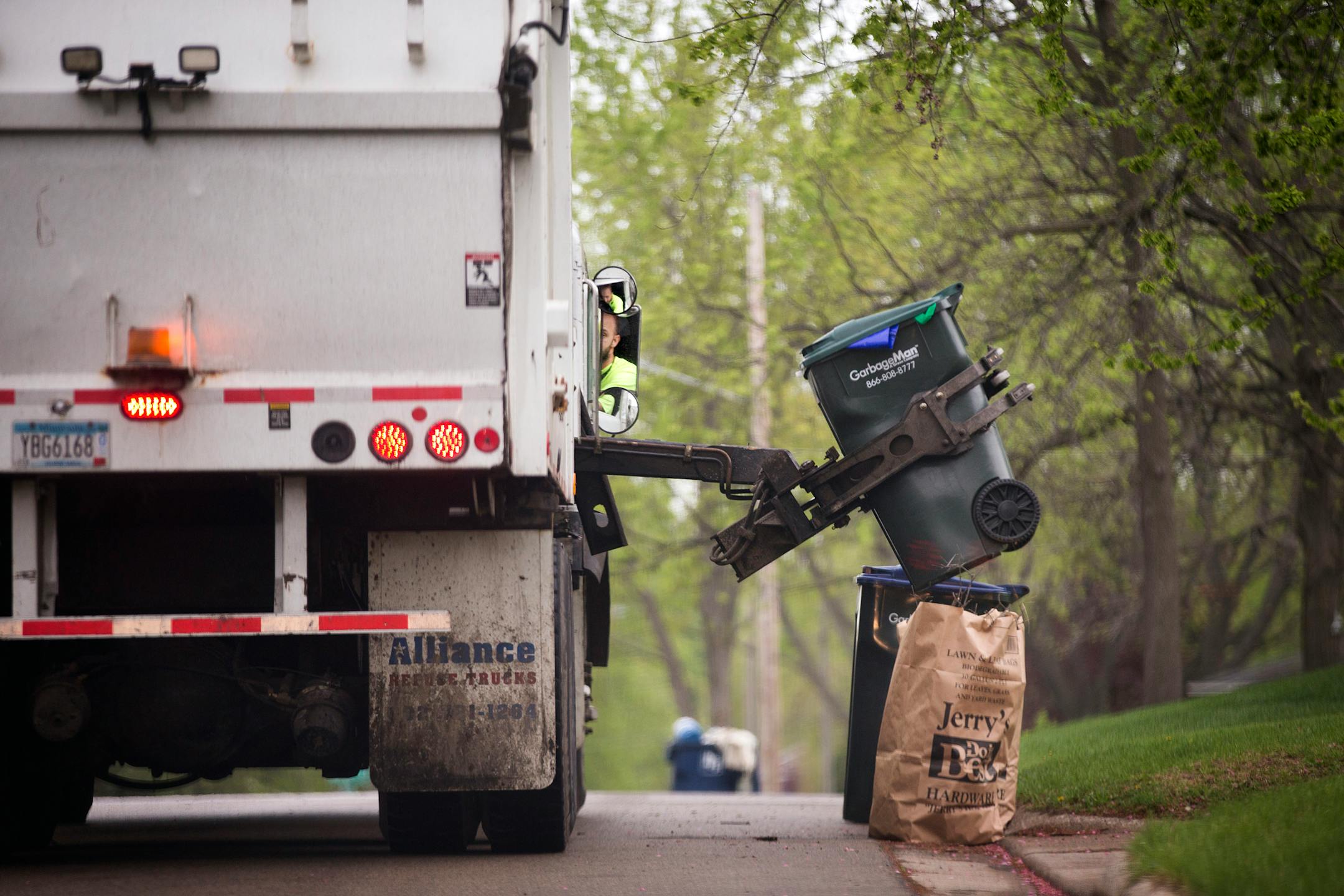 A trash collector empties containers onto the truck on trash pickup day.