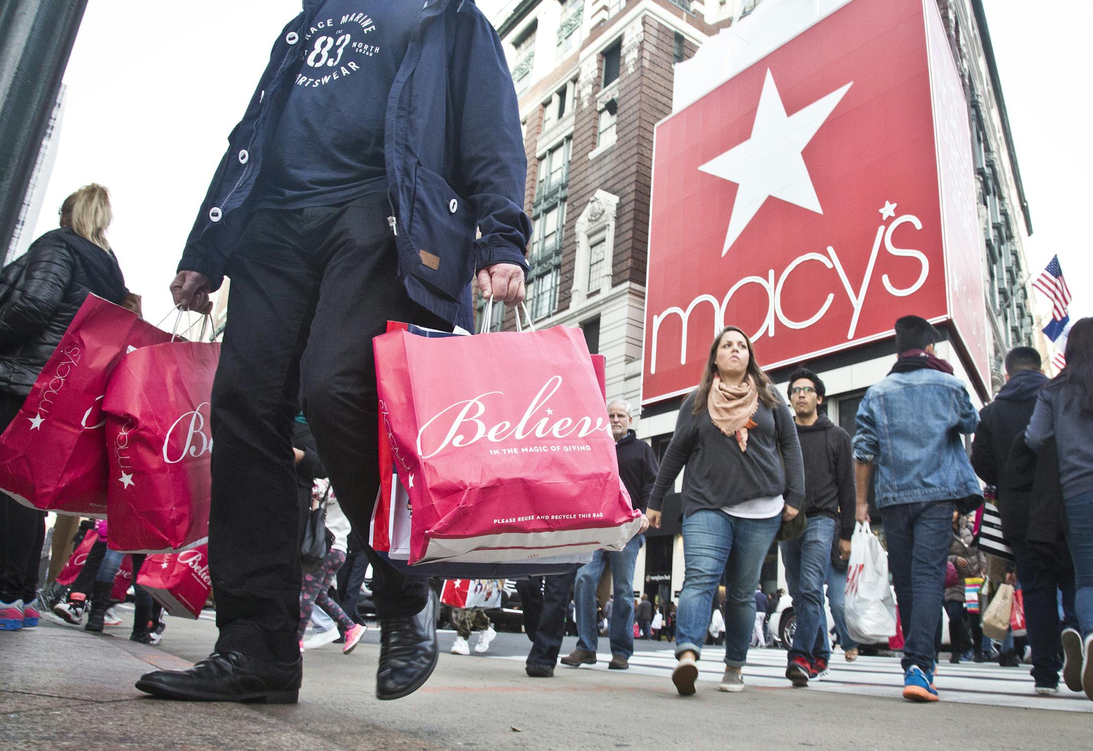 Shoppers carry bags as they cross a pedestrian walkway near Macy's in Herald Square, Friday, Nov. 27, 2015, in New York. The early numbers aren't available yet on how many shoppers headed out to stores on Thanksgiving, instead of waiting until today. But it's expected that more than three times the number who shopped yesterday will be out bargain-hunting today.