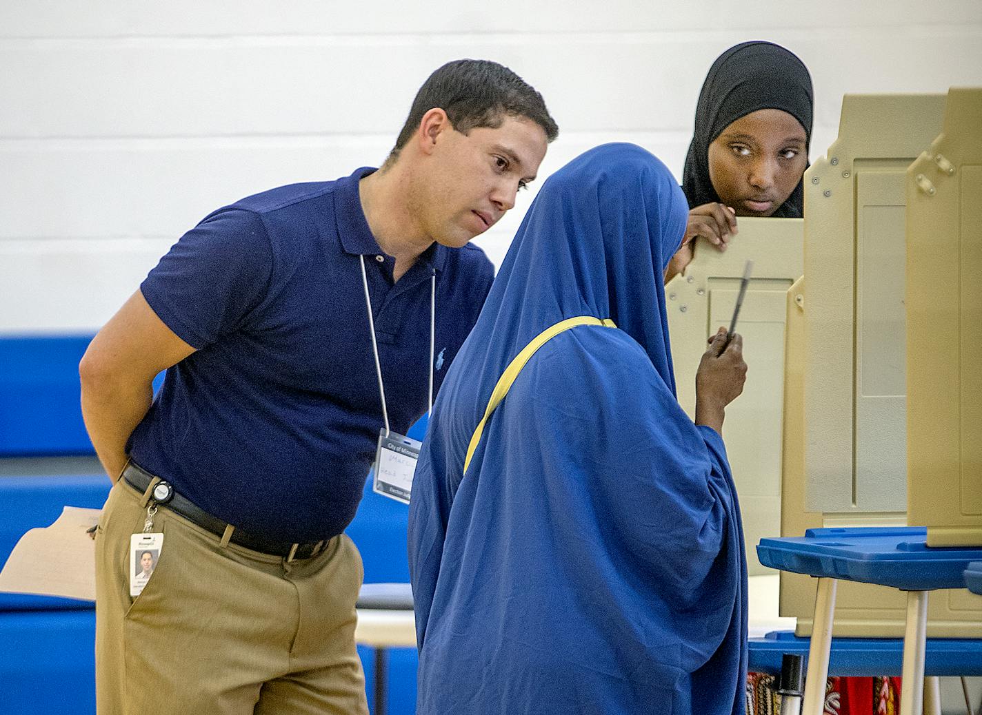 Election judge Marcus Singleton, left, and Salma Abdirahman, right, helped a voter at the Brian Coyle Community Center on primary election day, Tuesday, August 14, 2018 in Minneapolis.