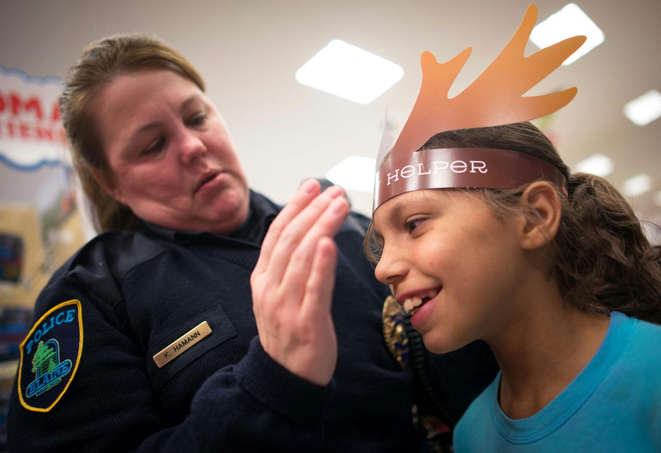 Blaine police officer Karen Hamann adjusts Charlise Webster's Heroes and Helpers reindeer antlers Tuesday night at Target. ] AARON LAVINSKY • aaron.lavinsky@startribune.com Anoka County cops and firefighters conduct their annual Heroes and Helpers event Tuesday, Dec. 2, 2014 at Target in Blaine. 48 children were given $100 gift cards to spend on themselves and their families while being escorted around target by first responders.