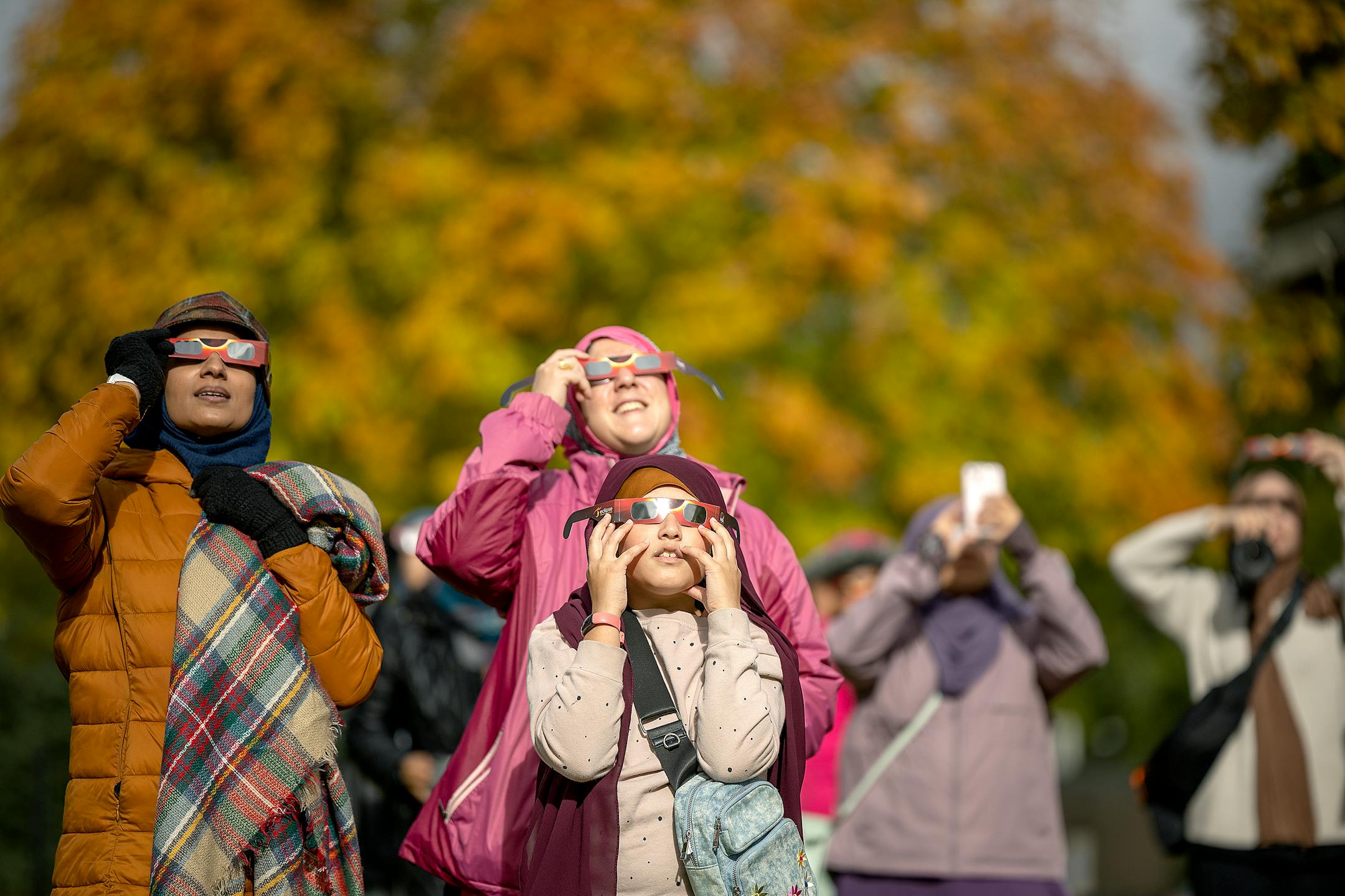 "A lot has been going on in the world and this is giving us a space and time and moment to pray to together," said Nausheena Hussain, cq, left, as she views the annular Eclipse alongside Laila Akhter, cq, center and daughter Zaiba Asif, cq, 10, during a viewing party at Commons Park in Fridley, Minn., on Saturday, Oct. 14, 2023.