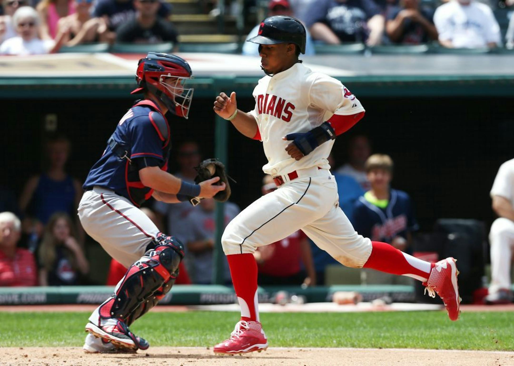 Cleveland Indians' Francisco Lindor scores past Minnesota Twins catcher Chris Herrmann on a sacrifice fly by Carlos Santana during the third inning of a baseball game, Sunday, Aug. 9, 2015, in Cleveland.
