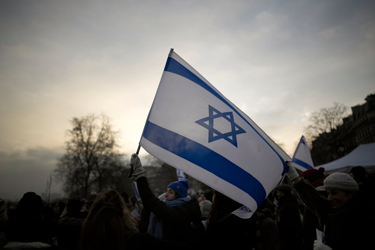 A demonstrator holds an Israeli flag during a rally to mark 100 days since the Oct. 7 attack, in Paris, Sunday, Jan. 14, 2024. Protesters gathered in 