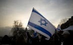 A demonstrator holds an Israeli flag during a rally to mark 100 days since the Oct. 7 attack, in Paris, Sunday, Jan. 14, 2024. Protesters gathered in 