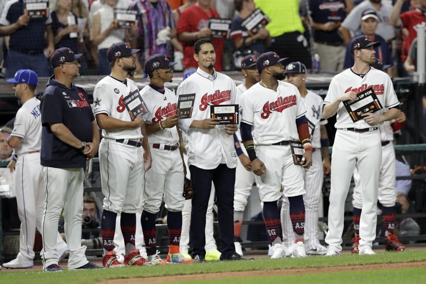 Cleveland Indians pitcher Carlos Carrasco, stands with Indians teammates during the fifth inning of the MLB baseball All-Star Game, Tuesday, July 9, 2019, in Cleveland. Carrasco, the Indians' right-hander, who was recently diagnosed with a form of leukemia, was saluted in the fifth inning of the game as part of Major League Baseball's "Stand Up to Cancer" campaign.