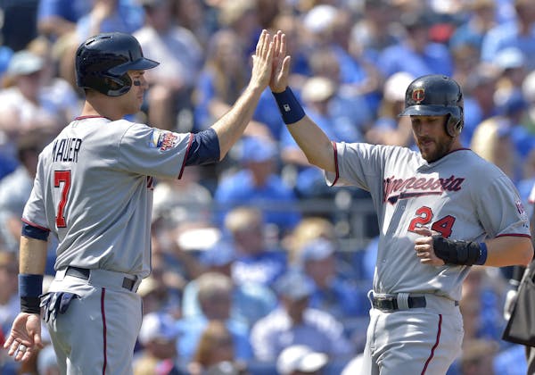 Minnesota Twins' Joe Mauer (7) and Trevor Plouffe (24) greet each other after both scored on a single by teammate Kurt Suzuki in the fifth inning agai