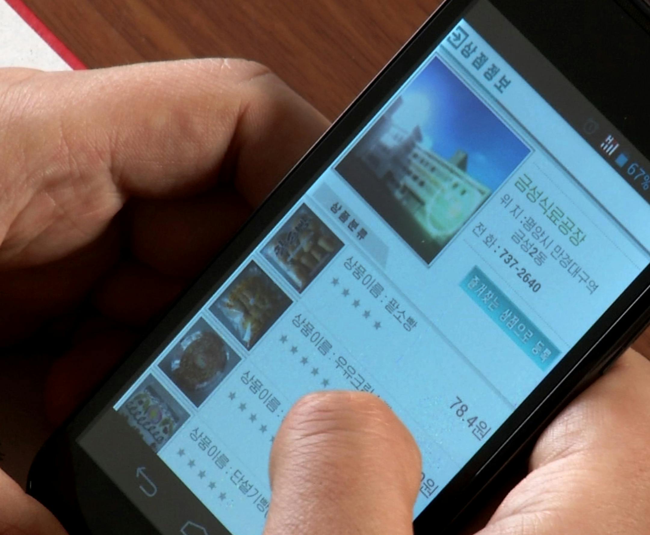 In this April 22, 2015, image taken from APTN, a man uses his smartphone to demonstrate how to use North Korea's new online shopping site,. North Korean officials have unveiled a mobile-friendly online shopping site that could give the nation its first taste of what many around the world have long seen as a mundane fact of modern life and provide local consumers with a rare opportunity to shop around for the best bargains. (AP Photo/APTN)