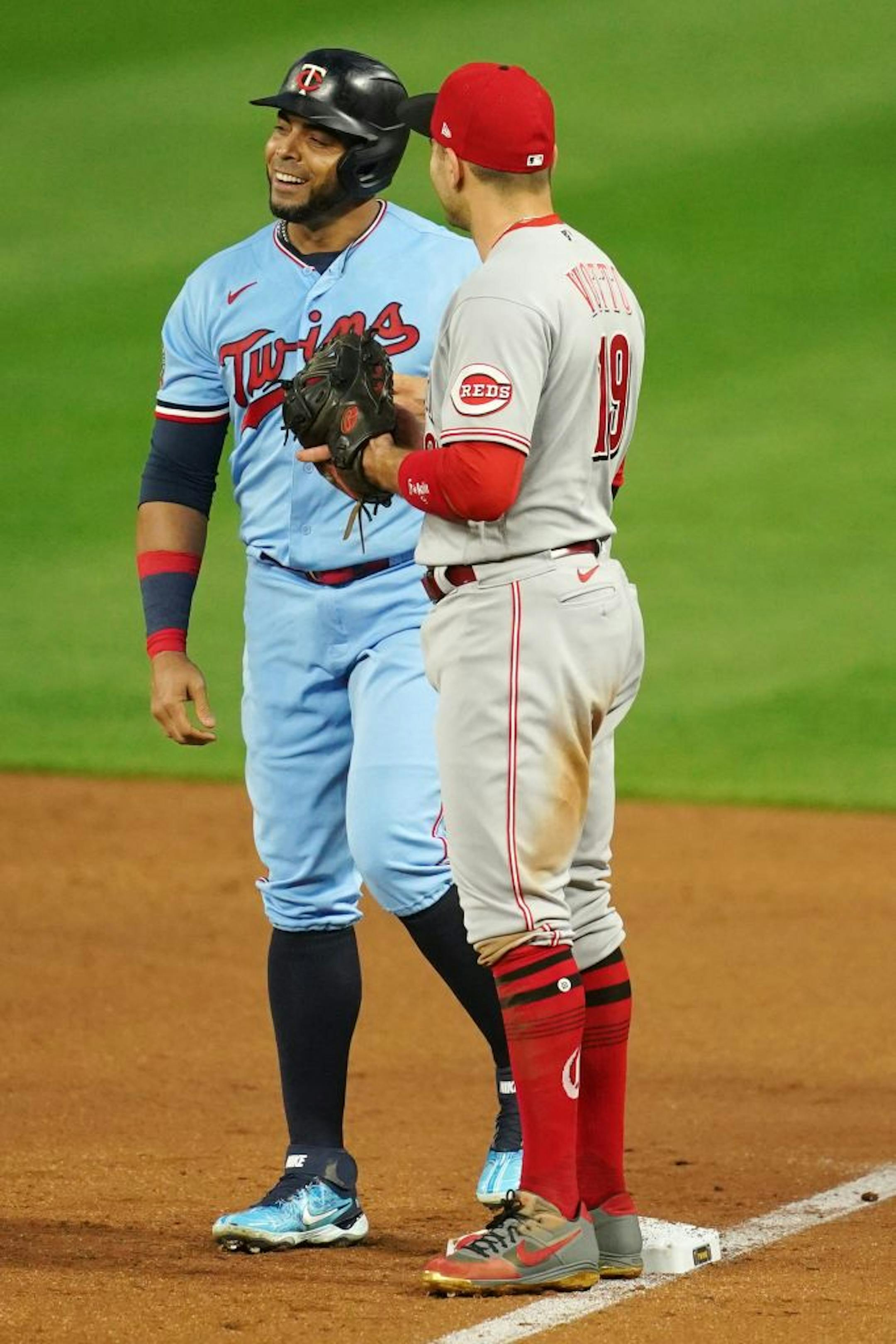 Minnesota Twins designated hitter Nelson Cruz (23) joked with Cincinnati Reds first baseman Joey Votto (19) after getting a single in the first inning.