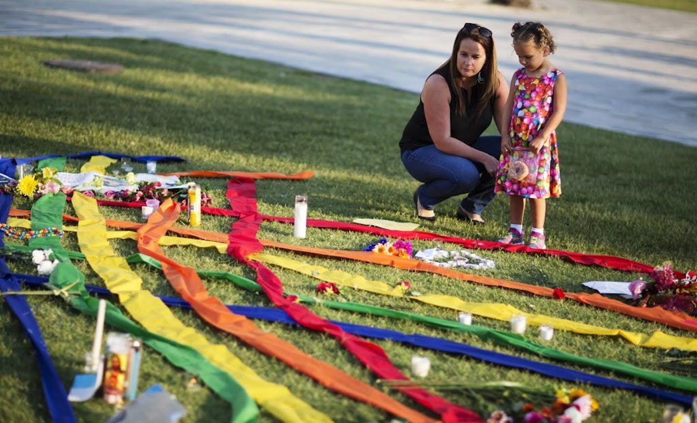 Rhonda Rodeffer, left, and her daughter Kennedy, 4, visit a makeshift memorial for the victims of a mass shooting at the Pulse nightclub Tuesday, June 14, 2016, in Orlando, Fla.