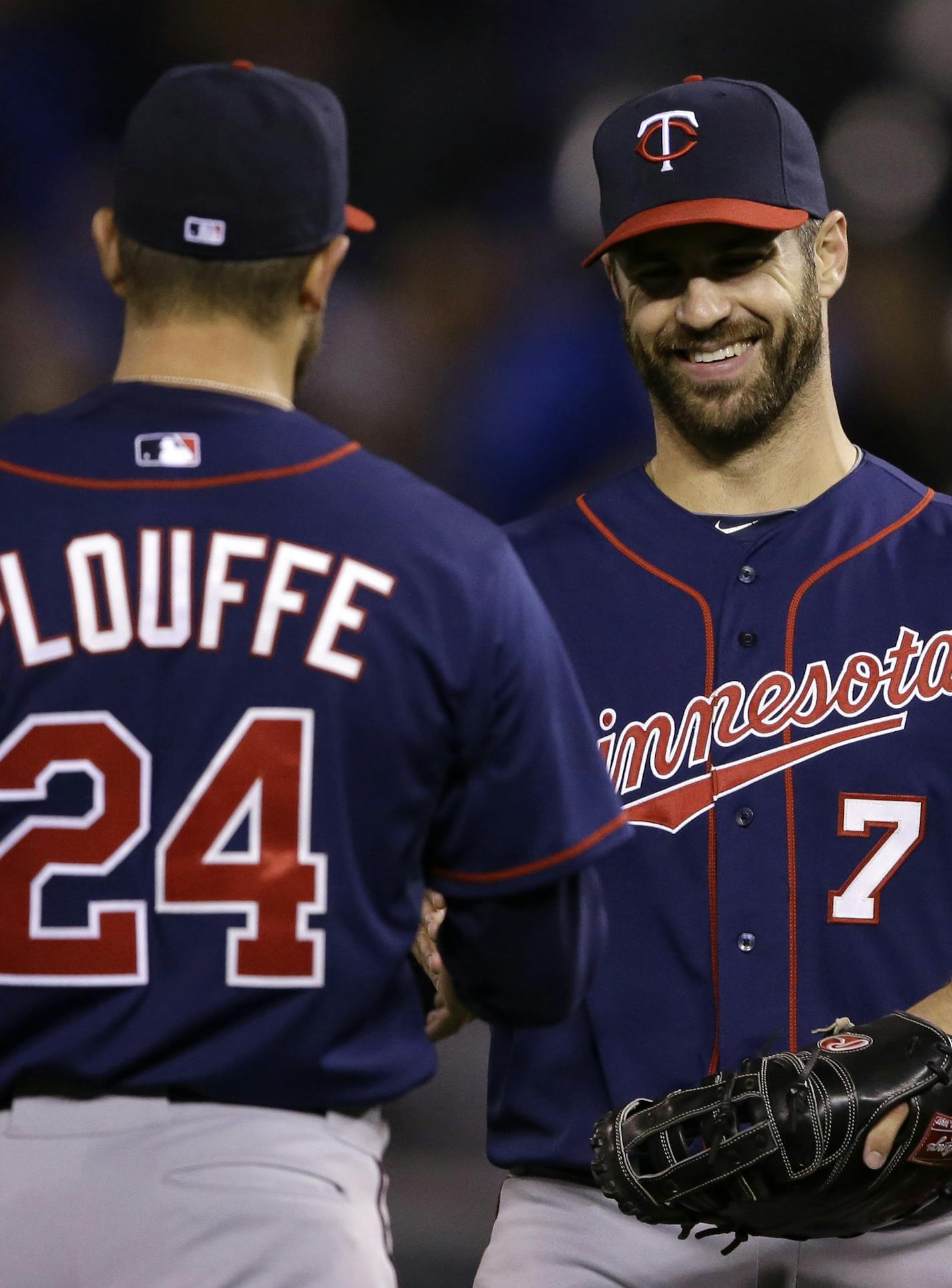 Minnesota Twins first baseman Joe Mauer (7) shakes hands with teammate Trevor Plouffe (24) following a baseball game against the Kansas City Royals at Kauffman Stadium in Kansas City, Mo., Wednesday, April 22, 2015. The Twins defeated the Royals 3-0. (AP Photo/Orlin Wagner)