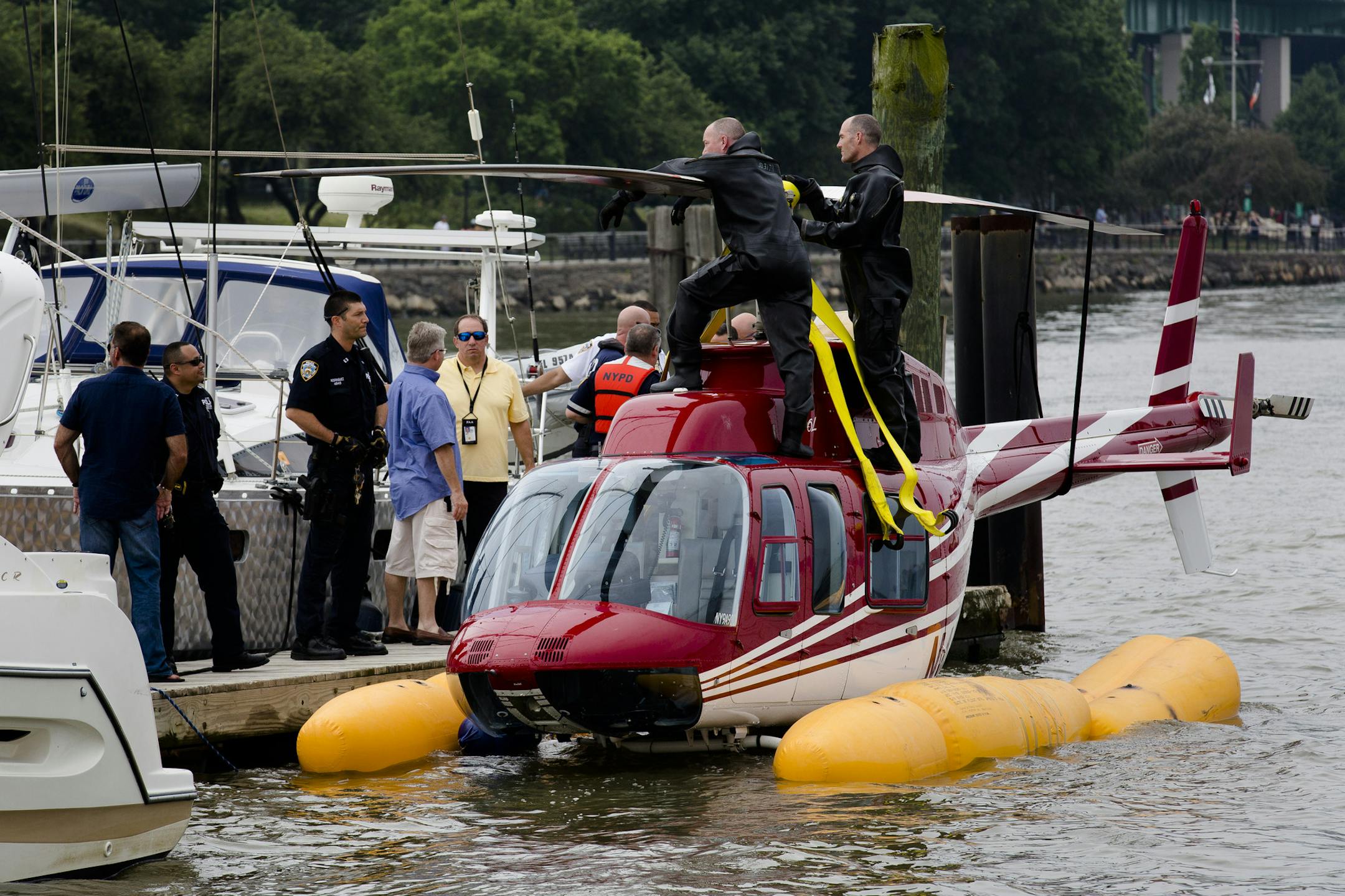 A helicopter rests on a pontoon at the 79th Street Boat Basin after an emergency landing over the Hudson river, Sunday, June 30, 2013, in New York. New York authorities say a helicopter carrying four Swedish tourists landed in the Hudson River off Manhattan Sunday, but everyone has been rescued. (AP Photo/John Minchillo)