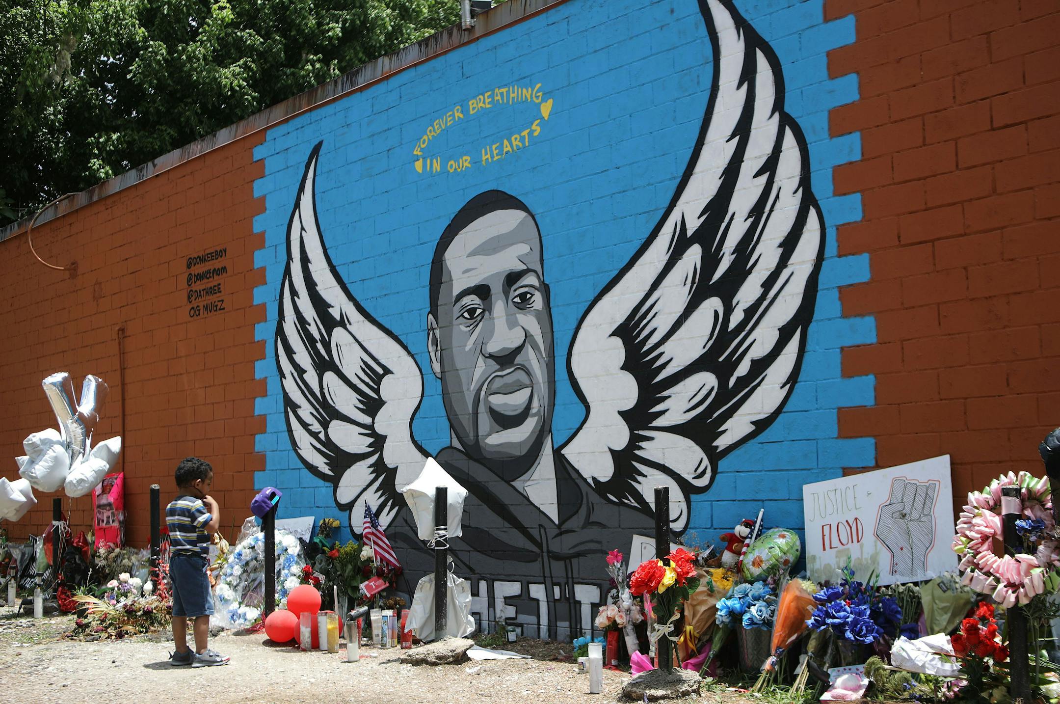 A child views a mural dedicated to George Floyd, across the street from the Cuney Homes housing project in Houston's Third Ward, where Floyd grew up and later mentored young men in June 2020. A 4-year-old girl who was shot while she was sleeping in her Houston home has been identified by local media as George Floyd's niece.