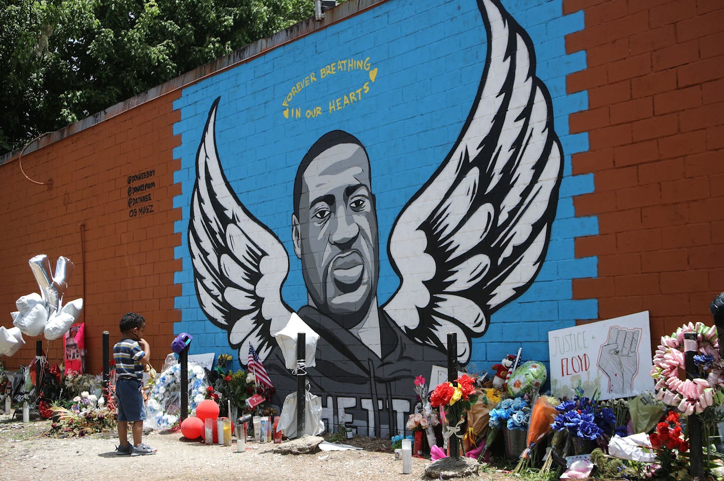 A child views a mural dedicated to George Floyd, across the street from the Cuney Homes housing project in Houston's Third Ward, where Floyd grew up and later mentored young men in June 2020. A 4-year-old girl who was shot while she was sleeping in her Houston home has been identified by local media as George Floyd's niece.