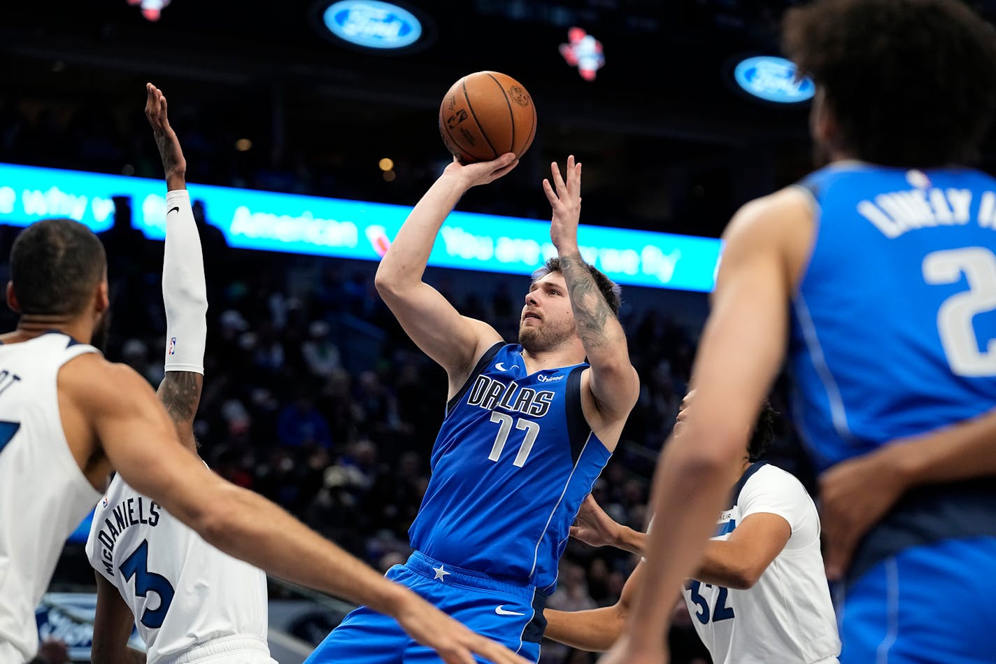 Dallas Mavericks guard Luka Doncic (77) shoots against Minnesota Timberwolves defenders Jaden McDaniels (3) and Karl-Anthony Towns (32) during the first half of an NBA basketball game in Dallas, Thursday, Dec. 14, 2023. (AP Photo/LM Otero)