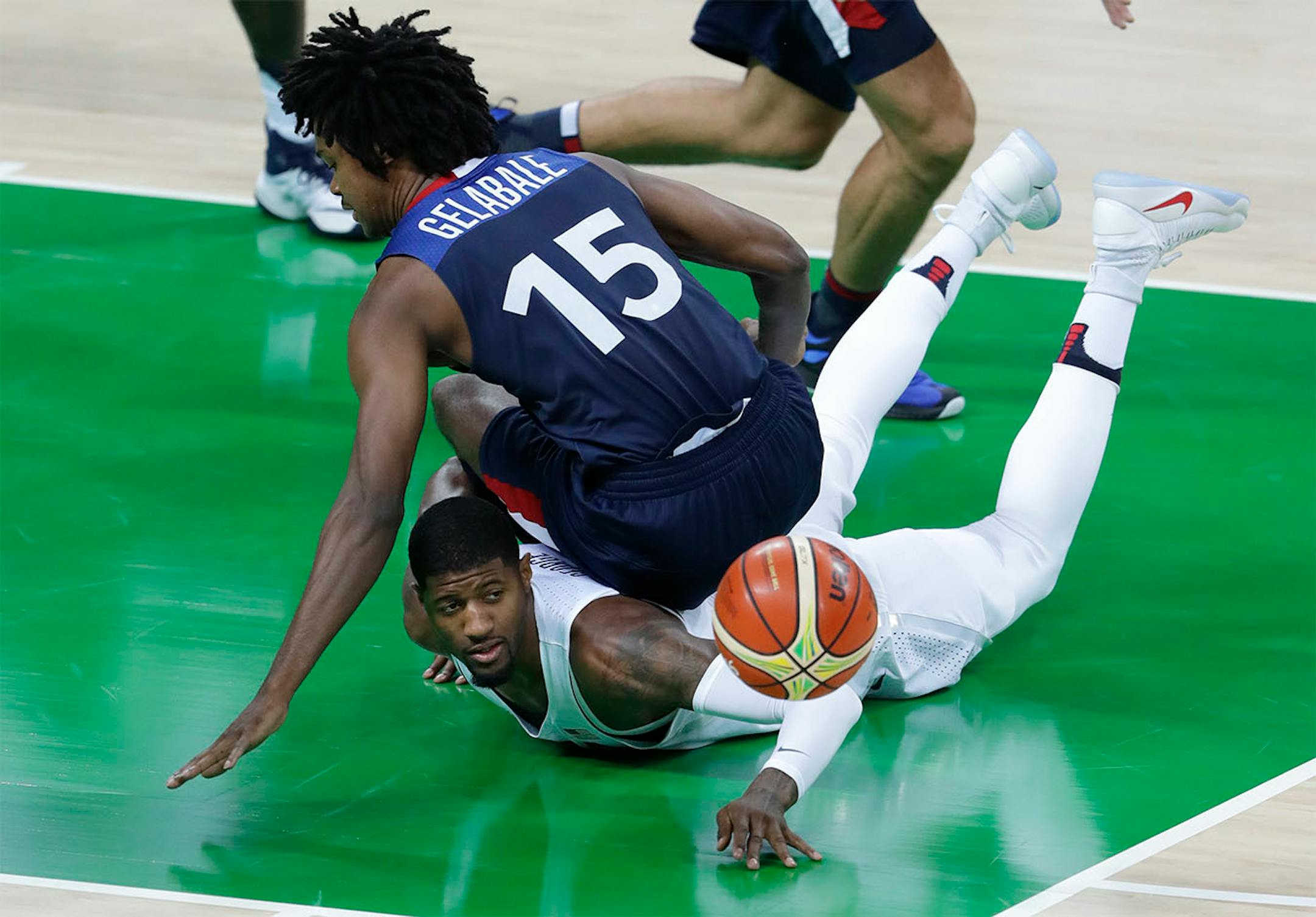 France's Mickael Gelabale (15) and United States' Paul George, bottom, fall to the floor as they chase a loose ball during a men's basketball game at the 2016 Summer Olympics in Rio de Janeiro, Brazil, Sunday, Aug. 14, 2016.