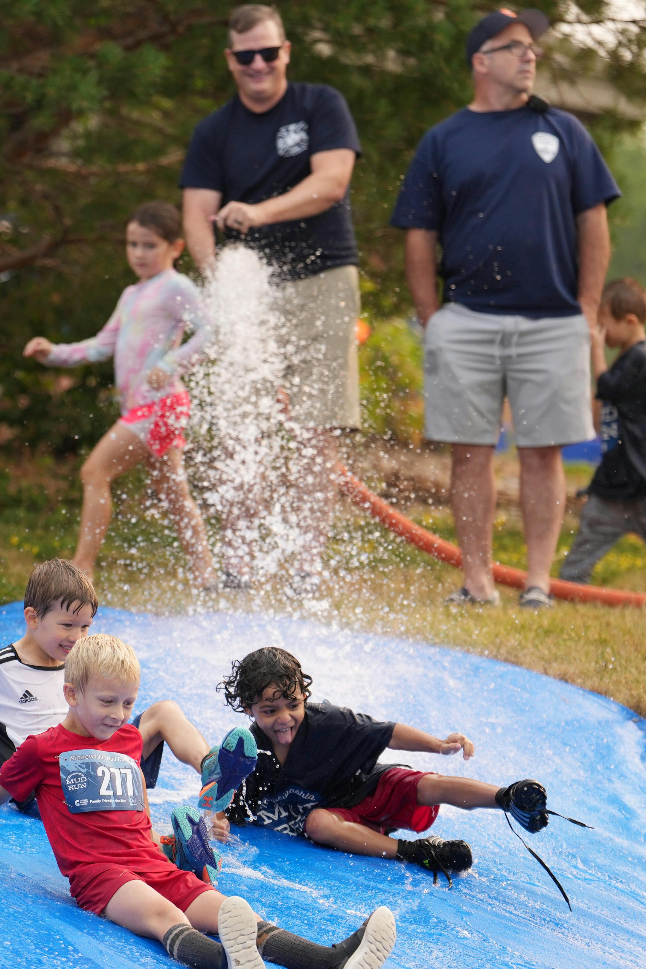 Chanhassen firefighters Bryan O'Keeffe and Dan Ryan use a fire hose to create a giant slip and slide.