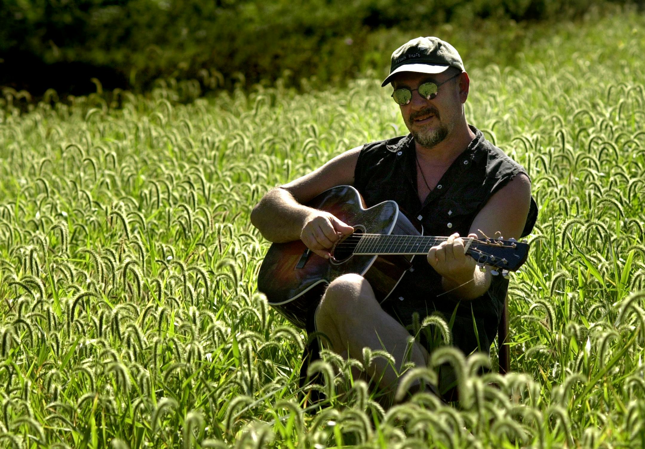 PUBLISHED CORRECTION Tuesday Sept 24, 2002, corrects identification of grass shown in this photo, which is foxtail, not oats. Caption below is corrected to say simply "a field." (JPhil) — GENERAL INFORMATION: Douds ,IA Monday 9/16/2002 GREG21: Even with such big names as Lucinda Williams, Shawn Colvin and Ani DiFranco singing his songs on a new all-female tribute CD, Iowa folk singer Greg Brown remains a reclusive cult hero. He took a year off from the music business to rebuild his grandparents 100-year-old farm and add a recording studio. We'll visit this locally-beloved folkie at the homestead in conjunction with the tribute CD's release and Brown's two shows Sept. 25-26 at the CedarCultural Center. IN THIS PHOTO: Greg Brown plays his guitar in a field on his farm. Brown was talking yesterday about trying to simplify his sound and maybe wants to record from this field.