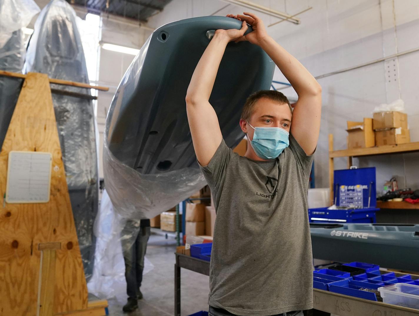 Lightening Kayaks production associate Zachary Sorensen carried the hull of boat Thursday morning. ] ANTHONY SOUFFLE • anthony.souffle@startribune.com Stuart Lee, owner of Lightening Kayaks, and his employees, including his father, worked on boats at their production facility Thursday, Oct. 1, 2020 in north Minneapolis. Lee has seen a 40% increase in sales as the result of a surge in outdoor recreation brought on by the Coronavirus and people looking for activities that lend themselves to being