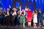 Gwen Walz, Governor Tim Walz, Hope Walz, Lieutenant Governor Peggy Flanagan, Siobhan Hellendrung, 9, and Tom Weber, left to right, raise their arms to