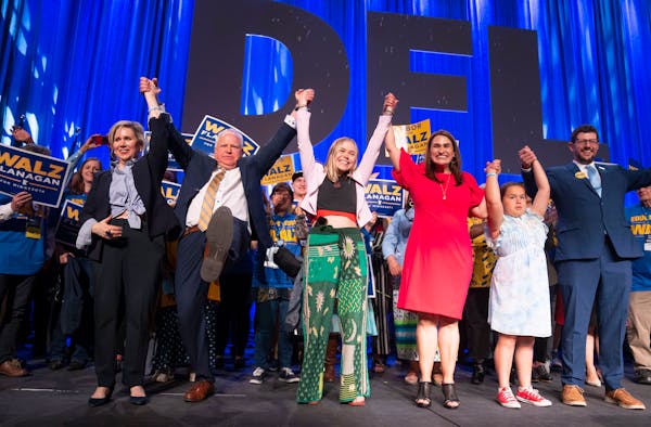 Gwen Walz, Governor Tim Walz, Hope Walz, Lieutenant Governor Peggy Flanagan, Siobhan Hellendrung, 9, and Tom Weber, left to right, raise their arms to