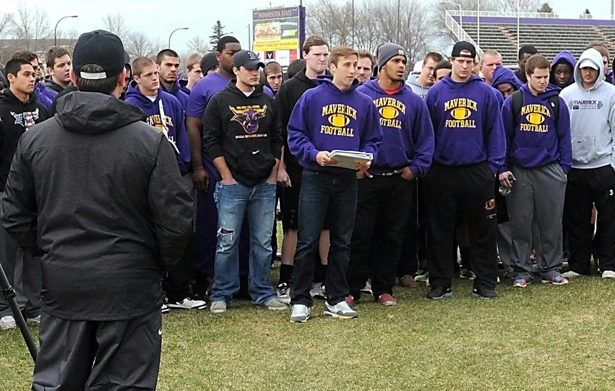 Player rebellion: Reinstated Minnesota State, Mankato football coach Todd Hoffner, in front, listened as football player Samuel Thompson, with the rest of the Mavericks team behind him, read a statement Wednesday in support of Aaron Keen.