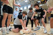 East Ridge basketball players cheer on Riley Hall as they compete with their teammates to properly use a test AED on a CPR mannequin Wednesday, Feb. 0