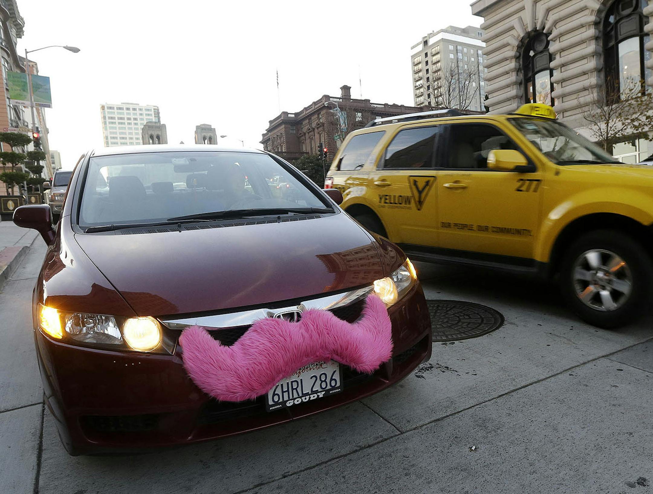 In this Jan. 4, 2013 photo, Lyft driver Nancy Tcheou waits in her car after dropping off a passenger as a taxi cab passes her in San Francisco. Fed up with traditional taxis, city dwellers are tapping their smartphones to hitch rides from strangers using mobile apps that allow riders and drivers to find each other. Internet-enabled ridesharing services such as Lyft, Uber and Sidecar are expanding rapidly in San Francisco, New York and other U.S. cities, billing themselves as a high-tech, low-cos