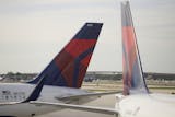In this Thursday, Nov. 29, 2018 photo, the tails of two Delta Air Lines planes are shown parked at the gates at Fort Lauderdale&#x2013;Hollywood International Airport in Fort Lauderdale, Fla. (AP Photo/Wilfredo Lee)