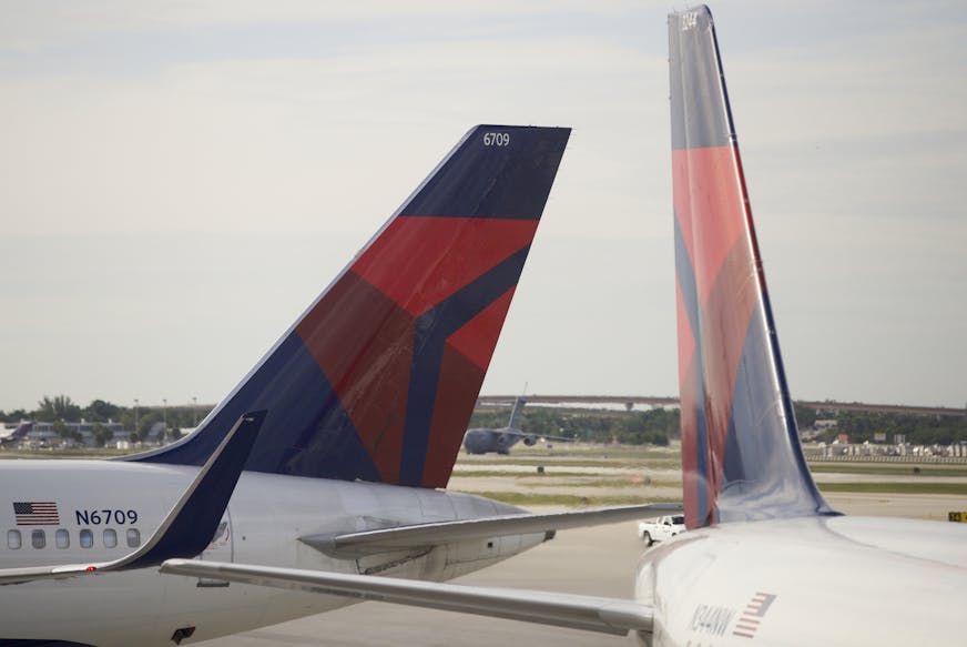 In this Thursday, Nov. 29, 2018 photo, the tails of two Delta Air Lines planes are shown parked at the gates at Fort Lauderdale&#x2013;Hollywood International Airport in Fort Lauderdale, Fla. (AP Photo/Wilfredo Lee)